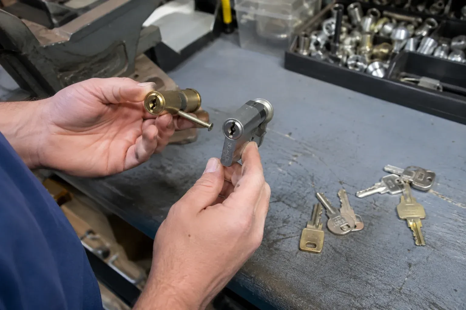 Hands comparing detached lock cylinders beside loose keys on a workbench. — Broken Key Extraction, Mississauga